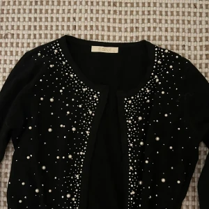 Cardigan  - Svart- Glittrig/pärl cardigan. Knappt använd. Riktigt söt.