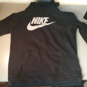 FET! Nike Hoodie - Svart o snygg Nike Hoodie. Mycket skön o har bra form funkar med nästan allt då den e mestadels svart och har vita detaljer👌. Mycket bra skick storlek 158 - 170 men skulle säga att den förmodligen passar närmar 160 än 170. 
