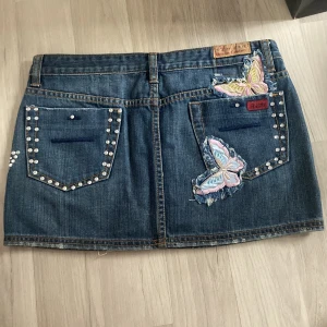 Jeans kjol -  jättefin denim kjol med fjärilar💗 jättemycket fina detaljer på bakre delen med diamanter runt fickorna och utklippta fjärilar samt en fjäril av diamanter på främre sidan. Köpt från märket Amara Jeans Denim Couture. Helt oanvänd och i nytt skick!💗