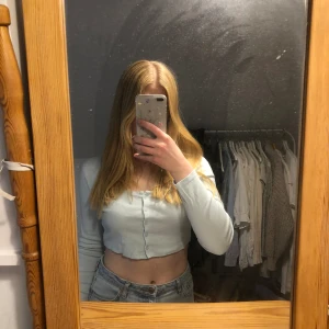 Ljusblå topp - Ljusblå croppad topp från hm. Knappar fram och långa ärmar, något ”tjockare” material än en vanlig t-shirt. Använd några få gånger. Storlek m men passar mig som har S i vanliga fall