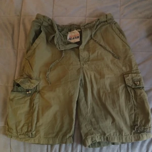 Vintage cargo jorts - Intressekoll på ett par snygga cargo jorts, perfekta nu när sommaren börjar närma sig så skicka rimliga bud🙌 Shortsen har en extremt snyggblekning och även ett inbyggt skärp/snöre. En knapp losnade så jag snydde tillbaka den med blå tråd(bild 4&5)❤️