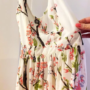 Blommig klänning  - Blommig sommarklänning med öppen rygg Smaka axelband som korsar varandra i ryggen  Körsbärsblommor 