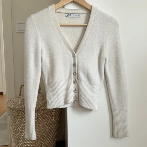 Vit tröja zara - Säljer denna snygga tröja/kofta från zara. Den är i ett så mysigt material, med de finaste knapparna. Den är använd men fortfarande i väldigt bra skick med inga defekter, men som man kan se på bilderna är den använd. Skriv för frågor eller annat 🙌🏼❤️