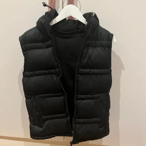 Väst - En svart lite varmare väst. Använd några gånger. I bra skick. Den har luva som man kan ta av. Säljer då den inte kommer till användning. Pris kan diskuteras 