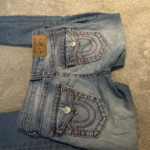 True Religion jeans - Säljer mina ljusblå true religion jeans, sömmarna är rosa och inget är slitet förutom att jag klippt en liten slits på dom för att få de lite mer bootcut! Vid midjan är de 36cm rakt över, ytterbenslängden är 101cm och innerbenslängden är 76cm💞