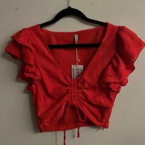 Fin röd kroppad top med snörning och volang, stl S - Jättebra skicka, ALDRIG använd. Prislapp kvar. Stl S