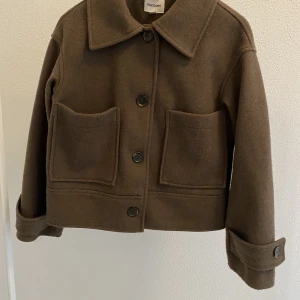 Brun kort kappa från Kappahl - Brun kort kappa från Kappahl, stl XS. Något nopprig, men i gott skick. Nypris 900 kr. Köparen står för frakten. 