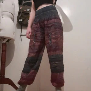 Färgglada byxor - Färglada pösiga byxor med ränder! Perfekt till din nästa hippie look;) Fickor på vardera byxben med trä pärlor hängandes från. Bra men använt skick. Säljer då de inte längre kommer till användning♡