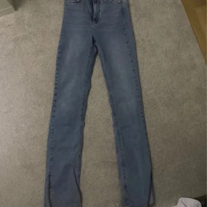 Jeans med slits - Blåa utsvängda jeans som är högmidjade. Köpta i Gina tricot och i storlek S. Använda en gång.