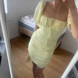 Adoore klänning - Gul kort Adoore klänning med snörning på sidorna. Köpt för ett tag sen men aldrig använd med båda lapparna kvar. Nypris 1200kr
