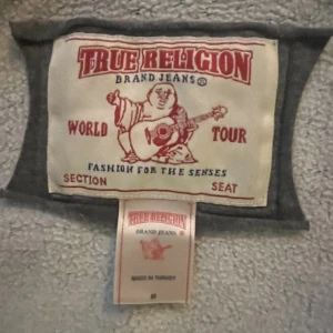 True religion hoodie - En grå true religion hoodie med randig luva. Storlek m🔥❤️ hoppas den kan få ett nytt hem