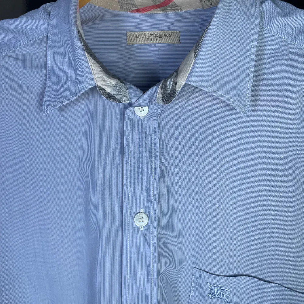 Kanske sommarens fetaste plagg. Fin ljusblå randig Burberry skjorta i finaste kvaliten med äkta perlemoknappar. Sjkortan är i fint skick. Passar Stort M till L. Om du har någon fundering är det bara att hoppa in i DM. Mvh StilKontoret. Skjortor.