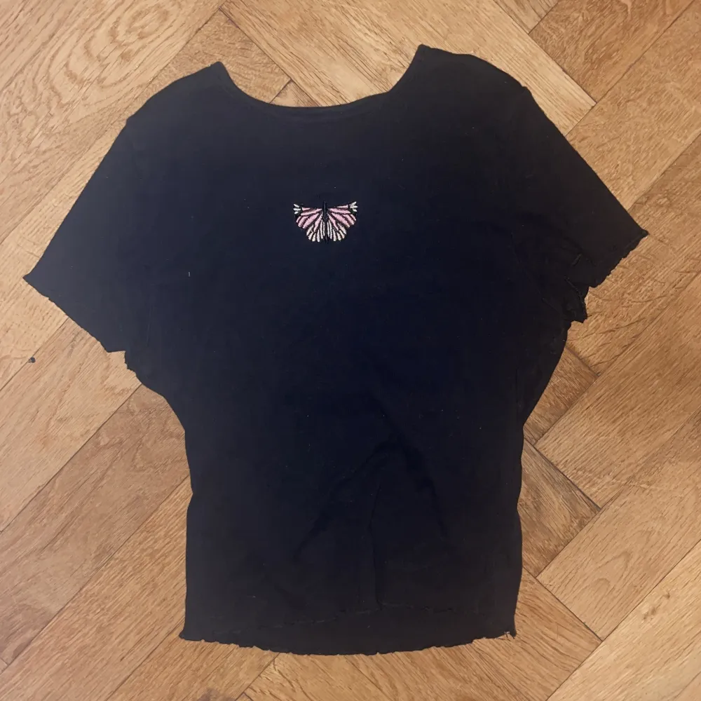 En croppad svart t-shirt med en broderad fjäril på bröstet. Frakt ingår inte i priset men priset kan diskuteras, om ni har frågor så skriv🫶. T-shirts.