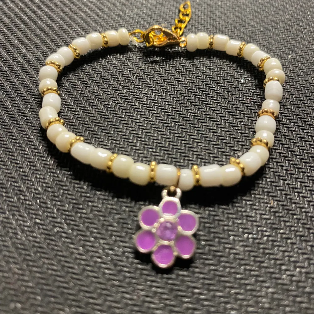 Sött armband med guldiga detaljer + lila blomma . Accessoarer.