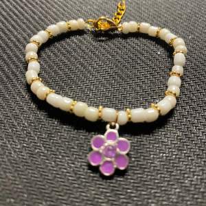 Sött armband med guldiga detaljer + lila blomma 