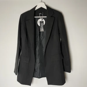 Kavaj - En svart, tunn kavaj från boohoo. Oanvänd, prislapp kvar. Säljer pga för liten. Storlek 36 men skulle uppskatta den mer som storlek 34. Köparen står för frakten. Går att få spårbart.