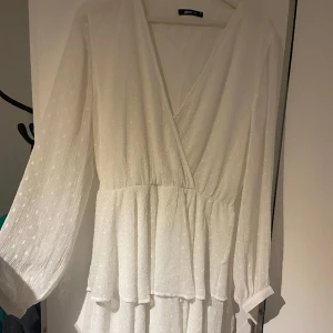 Klänning  - Sjukt fin vit klänning  Nyskick och perfekt till student eller skolavslutning. Volanger och bandi midjan. Storlek 44 