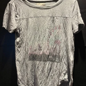 T-shirt - Grå T-shirt med motiv från Hollister i mjukt material.
