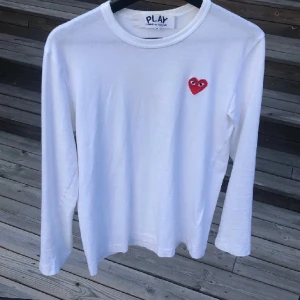 Long sleeve cdg t-shirt - En vit långärmad T-shirt köptes på Farfetch för lite mer än 1000kr. Idag 01/01-24 går den för ca 1800kr (ny)  Strlk S passar XS 9/10 i skick