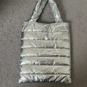 Liten Mac väska🩶 - Den är i bra skick den är ren får plats med mycket saker, den är 30cm bred och 36 cm lång utan *handtagen* om man inte ser är den silver och det står en vit text Mac på Texten sitter bra och är bra tryckt. Det är värt priset men kan diskuteras☺️