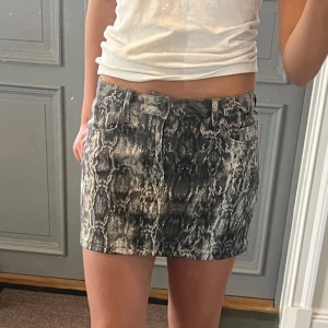 Mönstrad lågmidjad jeanskjol  - Lågmidjad mönstrad jeanskjol från Zara i storlek S som jag har sytt upp från en längre kjol. Tvärs över midjan är det 36 cm + stretch och längs med sidan är det ca 32 cm. Fint skick. Använd gärna köp nu!