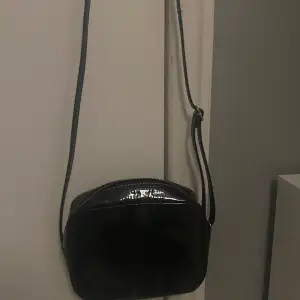En svart väska som glänser lite. Nästan aldrig använt denna , den ser helt oanvänd ut.
