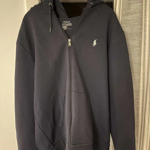 Ralph Lauren zip up hoodie - Ralph Lauren full zip hoodie, i mörkblå färg och i storlek S. Använd varsamt och i väldigt bra skick. Nypris 2 000.