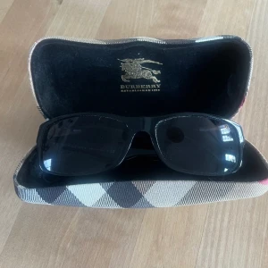 Solglasögon Burberry - Fina solglasögon från Burberry, litet märke på ena glaset som inte märks med glasögonen på och endast synligt vid riktigt noggrann granskning. Fodralet har märken efter 10 års användning.  Mycket fint helhetsintryck 8/10 