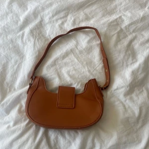 Handväska  - Brun väska med guldiga detaljer. Helt oanvänd 