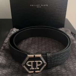 Philipp plein bälte - Jag säljer mitt svarta philipp plein bälte som är köpt på johnells och är i storlek 95. Nypris på bältet ligger på 5699kr. Dustbag, box och kvitto ingår
