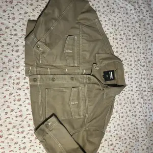 En khaki/oliv/beige jeansjacka från Dr. Denim i storlek XS. Jackan har långa ärmar, knappar framtill och två bröstfickor med lock. Den har en liten fläck på baksidan. Snygg oxh lite kortare passform. Nypris ca 899kr.