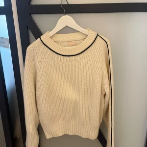 Stickad tröja med svart detalj - Säljer denna superfina tröja med svarta detaljer i blandad ull från hm! Använts fåtal gånger men kommer tyvärr inte till användning.  Noppar sig ganska lätt men det går lätt att ta bort.