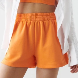 Orange shorts - Ett par orange shorts med elastisk midja. Shortsen har en lös passform och är tillverkade i ett mjukt material.