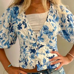 Blå och vit blus - Säljer en av mina finaste blusar som är dekorerad med blåa och vita blommor. Blusen har lite puffiga armar och är perfekt att ha nu i sensommaren. Tröjan har inga defekter och är i mycket bra skick💙💙💙