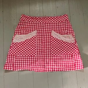 Rutig Kjol - Rutig kjol med blommiga detaljer vid fickorna. Storlek 38 men skulle säga att den passar S-L beroende på hur en vill att den ska sitta. Hör av dig om du har några frågor! 