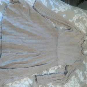 Beige ribbad klänning - En beige ribbad klänning med långa ärmar. Klänningen har en enkel och elegant design, perfekt för både vardag och fest.