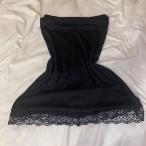 Svart tube top med mesh detaljer - En elegant svart tube top med mesh detaljer längs nederkanten. Toppen är av normal passform och har en enkel, stilren design. Nypris - 350kr. 