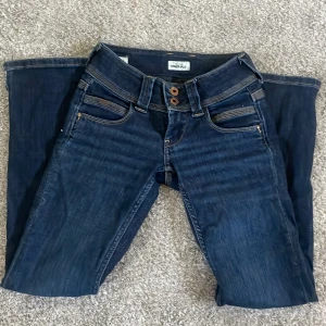 Blå jeans från Pepe Jeans - Ett par blå jeans från Pepe Jeans med modellnamnet Power Flex. Jeansen har en klassisk femficksdesign och är tillverkade i ett stretchigt material för extra komfort. De har en låg midja och en Bootcut passform.