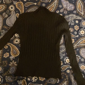 Tight långärmad med krage - Detta är ett plagg som sitter tight mot kroppen och har en liten polokrage. Den har även ett slags ribbat mönster. Tröjan är i bra skick!