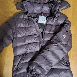 Moncler jacka - Ny skick, köpt för 14000 kr från NK, dam jacka i färgen lila. Jackan är i storlek L men den passar mer som Xs och S. Jag säljer den eftersom jag vill köpa en ny jacka eller så kan jag byta med någon.