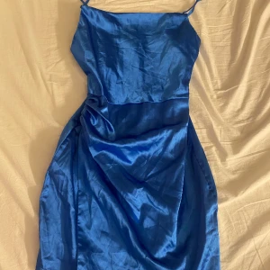 Klänning  - Denna är bara använd 1 gång så det är bra skick, glansig i materialet och faller fint där fram. 