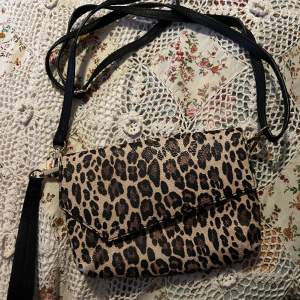 Leopardmönstrad väska från DON DONNA. Färgen har gått bort lite vid nedre hörnen men annars i mycket fint skick. Jätte fin och ren på insidan också. Måtten är 20x15 cm. Ett justerbart band och ett mindre svart band tillkommer. 