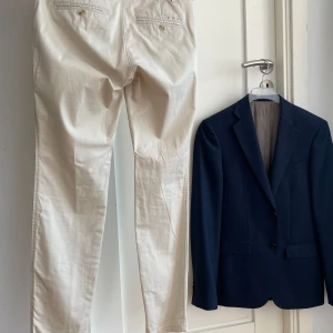 Blazer/ kavaj och beiga chinos - Använt 2ggr. Stl: 36 (s) i Bondelidbyxor och 44(s)  i Bläckkavaj. Kille som haft var 1,68 lång och normalvikt. Kavaj slimfit och byxorna sitter fett snyggt på. Likt de på bilden. Inköpt på MQ. NyprisBlazer 1999 och byxor 700. Pris för båda 995 kr