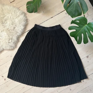 Svart Plisserad midikjol - Plisserad midikjol i svart. Gummiband i midjan. Använd endast fåtal gånger.