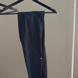 Träningstights svarta under armor - Svarta tights storlek M från under armor. Blank detalj på vaden,  en liten ficka på låret. Använt skick