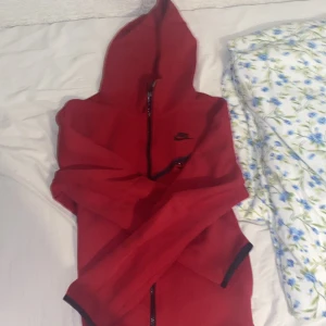 Nike tech fleece röd - Riktigt fet tech fleece haft den i ett år använde den nåra gånger förra året men tröttna och ville inte ha den annars fet inga hål men nåra saker p dragkedjan har gått av pga av tvätten OBS 300 KR EXTRA FÖR BYXOR‼️