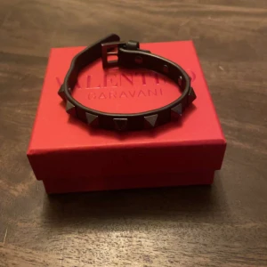Valentino armband - Svart valentino armband i bra skick, endast ett litet märke där man spänner. Box, dustbag och kuvert medföljer