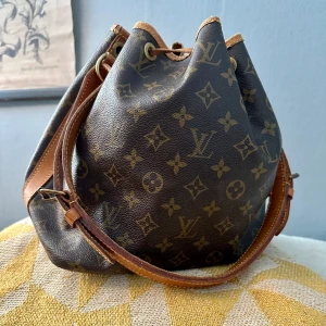 Louis VuittonNoe cloth handbag vintage  - 90-tal second hand Louis vuitton, fint ex för sin ålder. Datecode AR0956 innebär att den är tillverkad vecka 05 år -96. Säljes i befintligt skick! Mycket fin trots slitageVäldigt lätt och behändig väska. Lädret behöver behandlas med olja eller fett. 