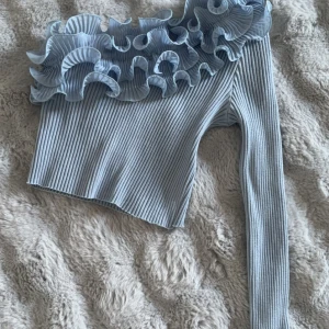 Fin tröja  - Kort med volanger och en arm Är liten i storleken  Ljusblå