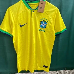 Brasilien fotbollströja - Säljer min helt nya Brasilien tröja från säsongen 22/23! Riktigt snygg och perfekt i sommar. Fick den i present så är lite osäker på autenciteten. Storlek S men passar också M! Har alla lappar och påsen kvar! Vid frågor hör gärna av dig! 💫⭐️